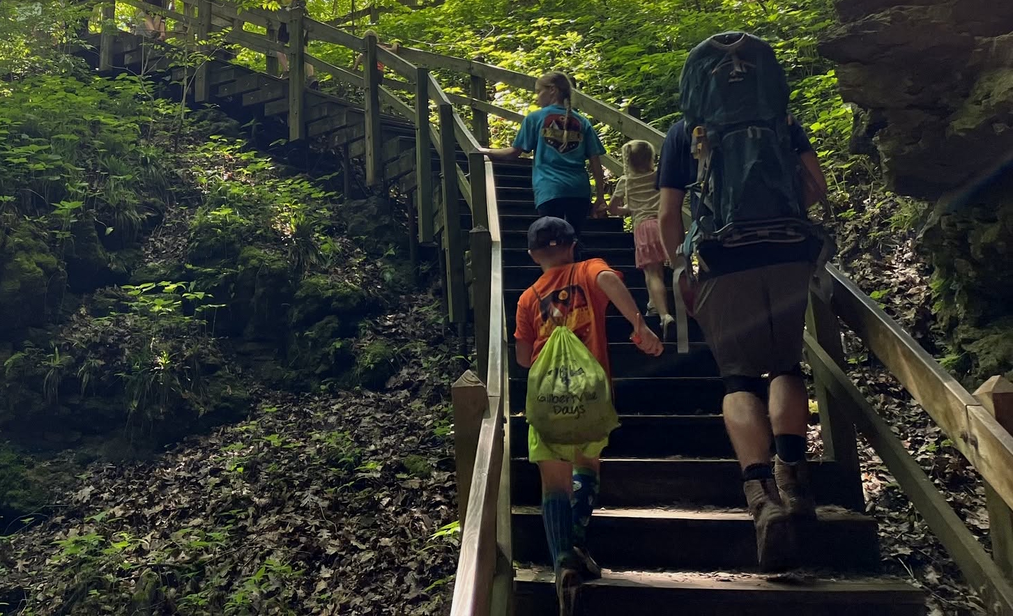 A family resting on a rocky trail beside a forest river